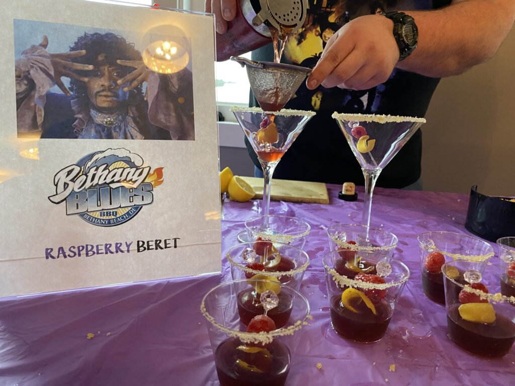 a man pouring drinks into martini glasses on top of a purple table