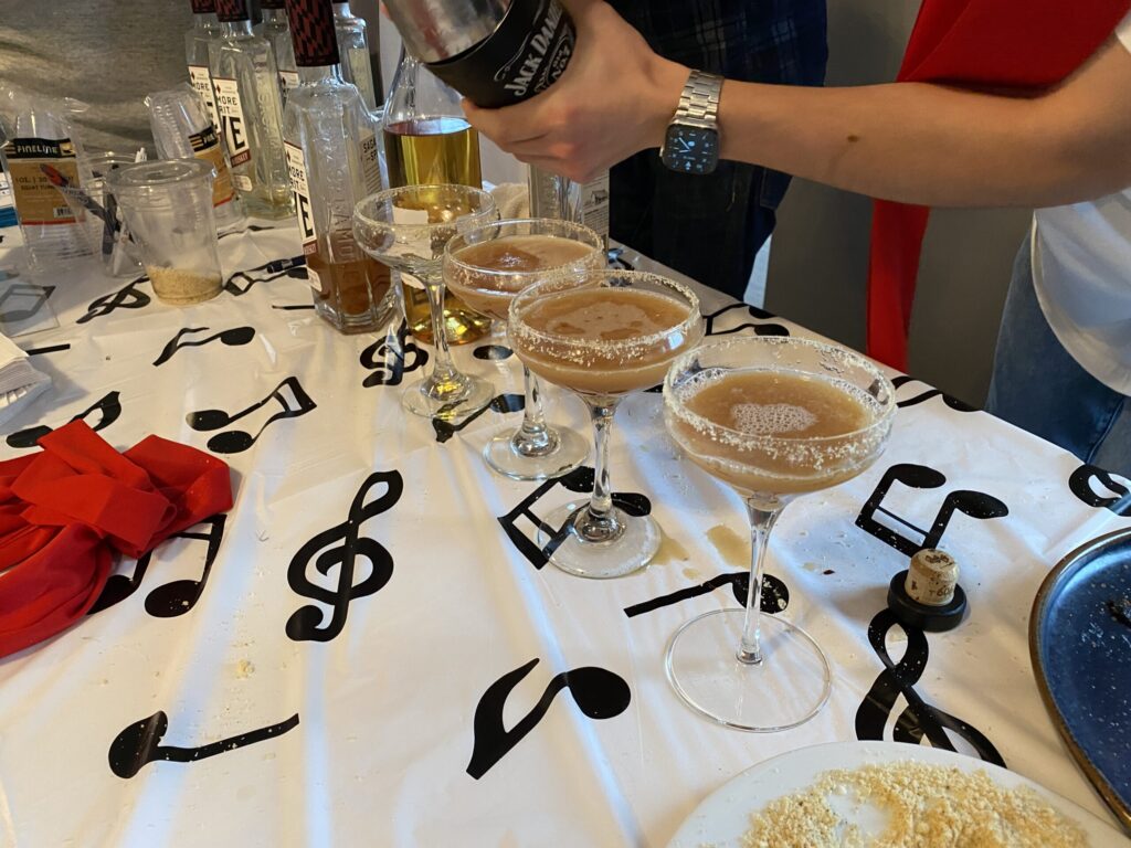 a group of people standing around a table filled with food and drinks