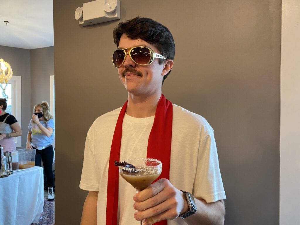 a man wearing sunglasses and a scarf holding a drink