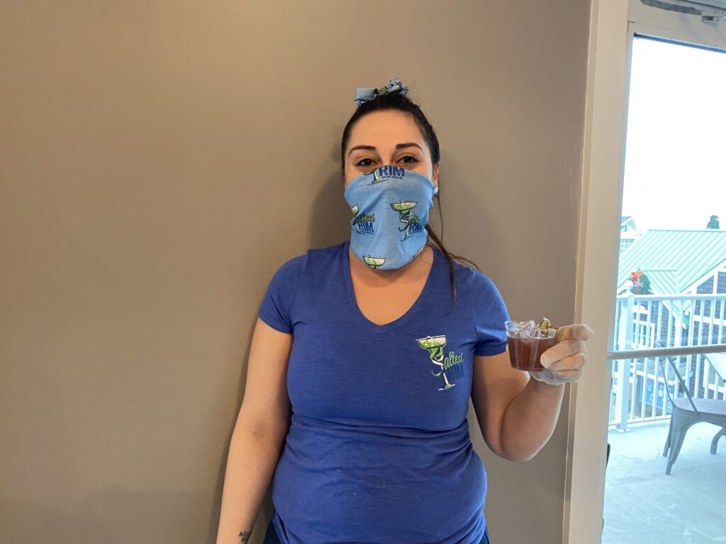 a woman wearing a face mask holding a cup of coffee