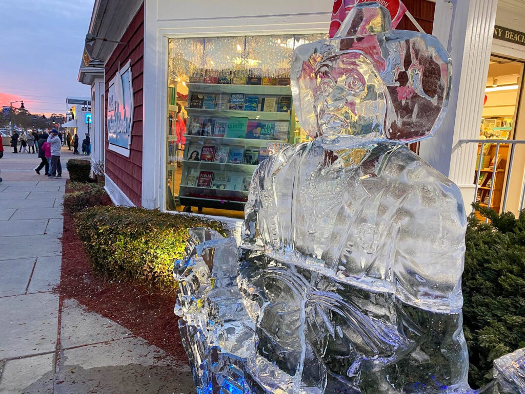 an ice sculpture of a man sitting on a bench in front of a store