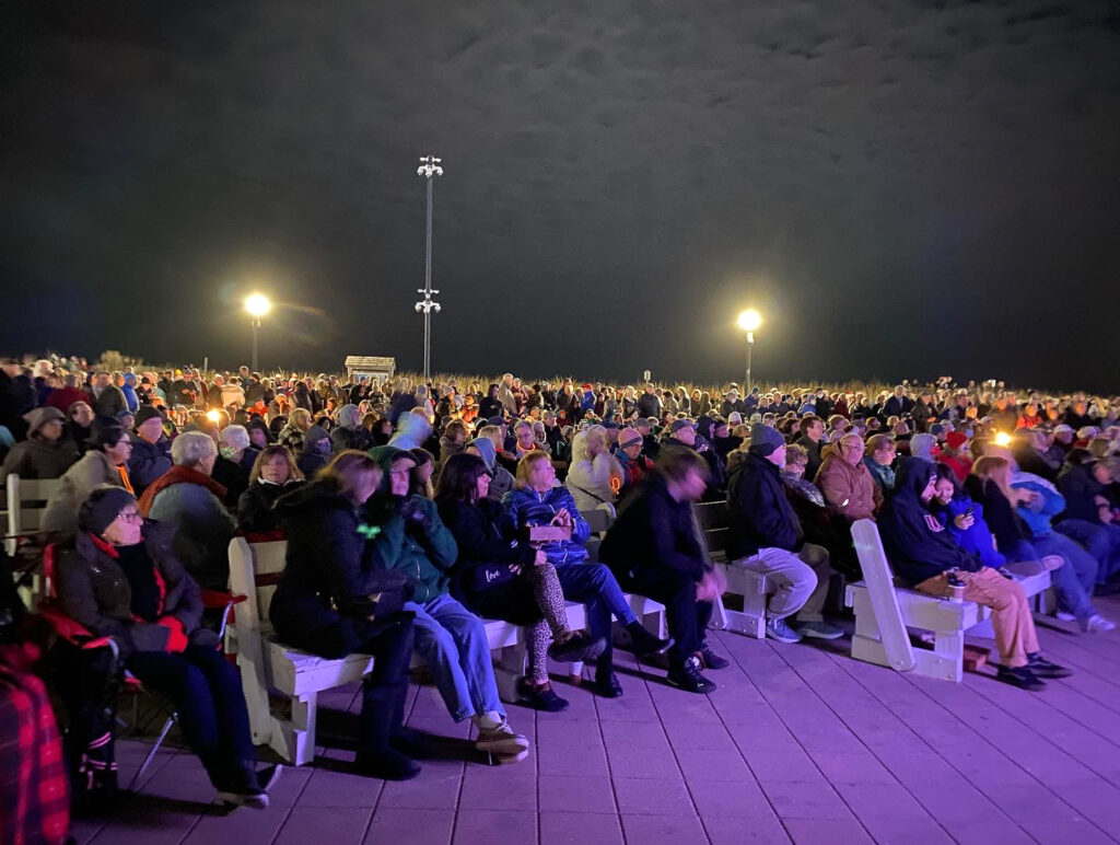a large crowd of people sitting on top of a wooden floor