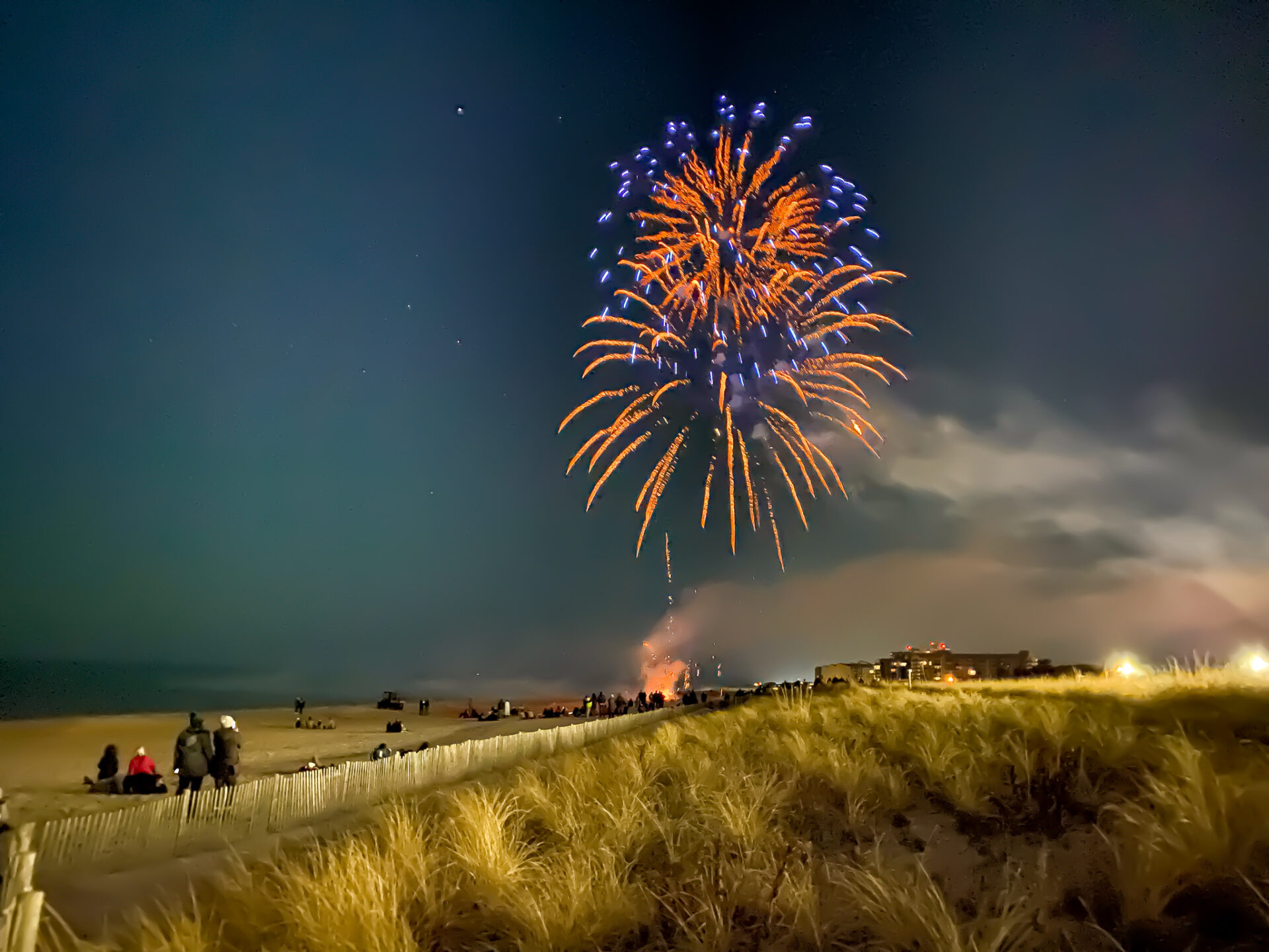 a fireworks display on the beach with people watching