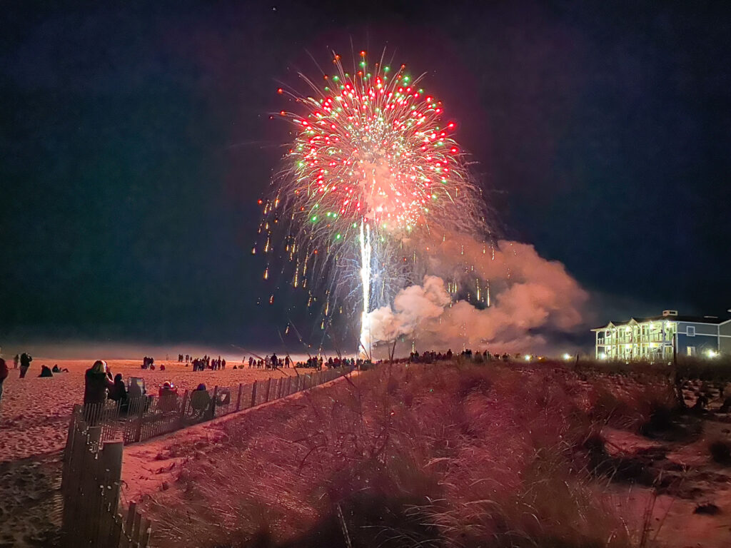 fireworks on the beach at night with people watching