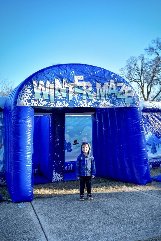 a little boy standing in front of a blue winter maze