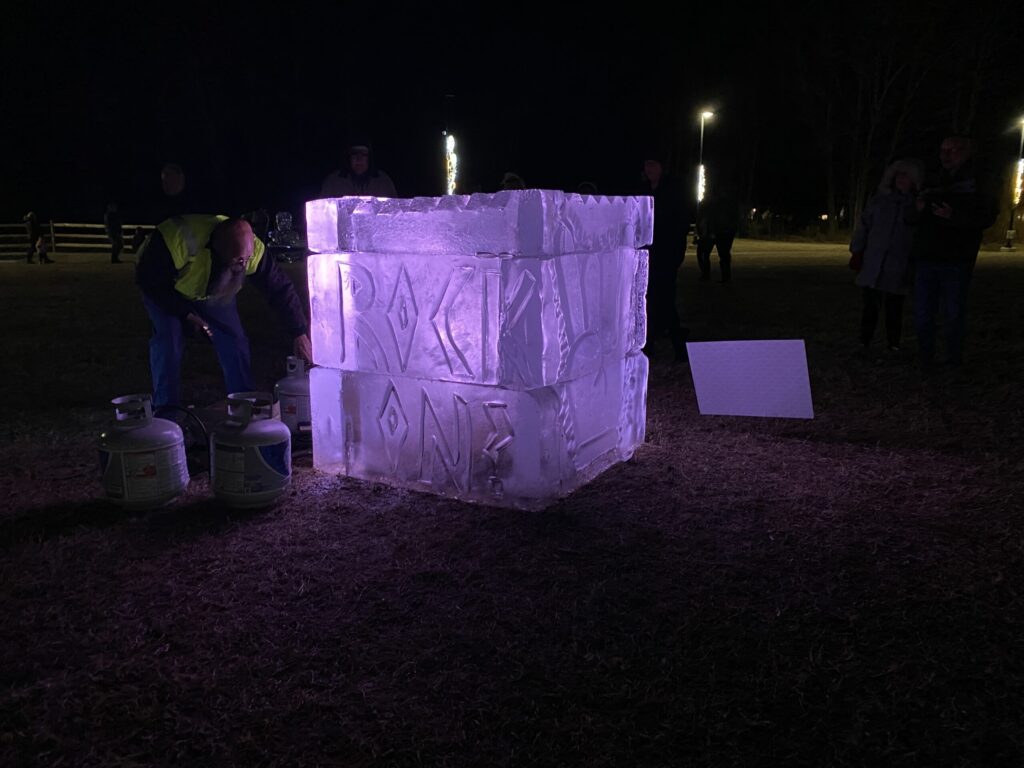 a group of people standing around a large ice block
