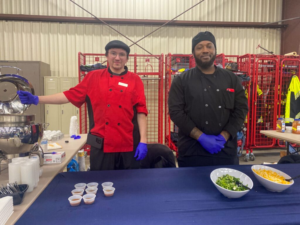 a couple of men standing next to a table