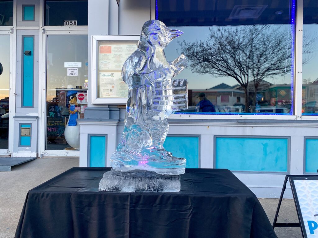 an ice sculpture of a man holding a fish in front of a building