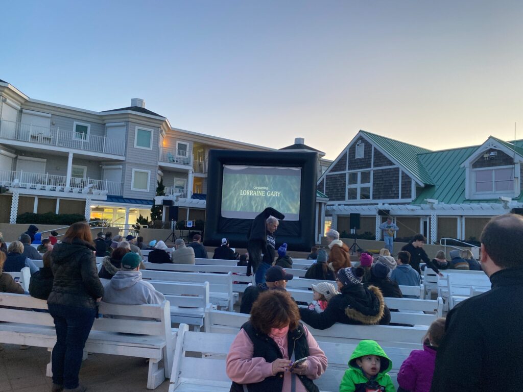 a group of people sitting on benches in front of a movie screen