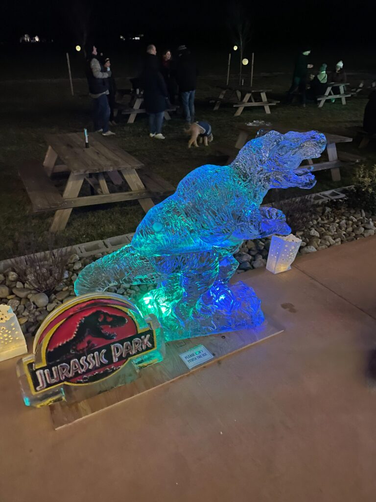 a lighted statue of a dinosaur in a park at night