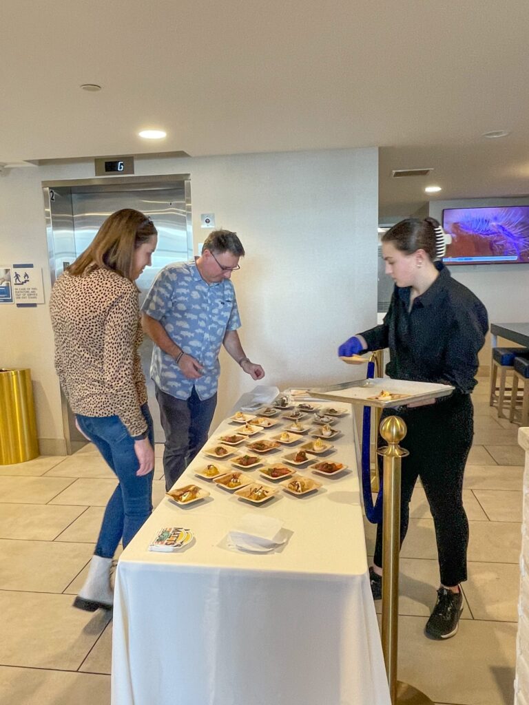 a group of people standing around a table with food on it