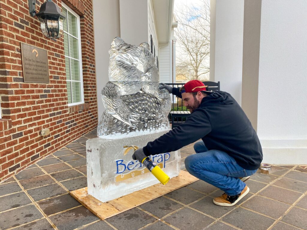 a man painting a statue of a bird on a sidewalk