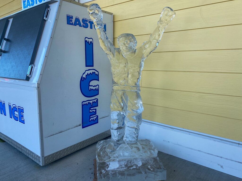 a ice sculpture of a man standing next to an ice machine
