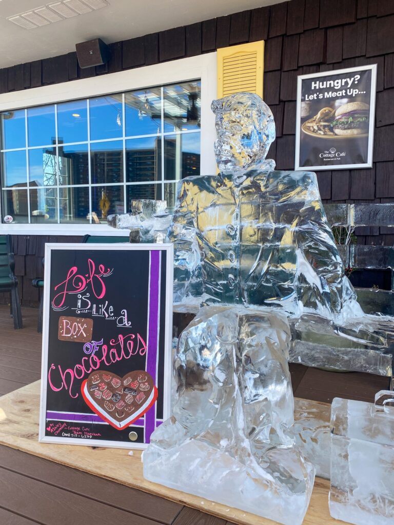 an ice sculpture of a man sitting on a bench in front of a building