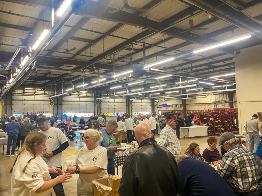 a group of people standing around tables in a warehouse