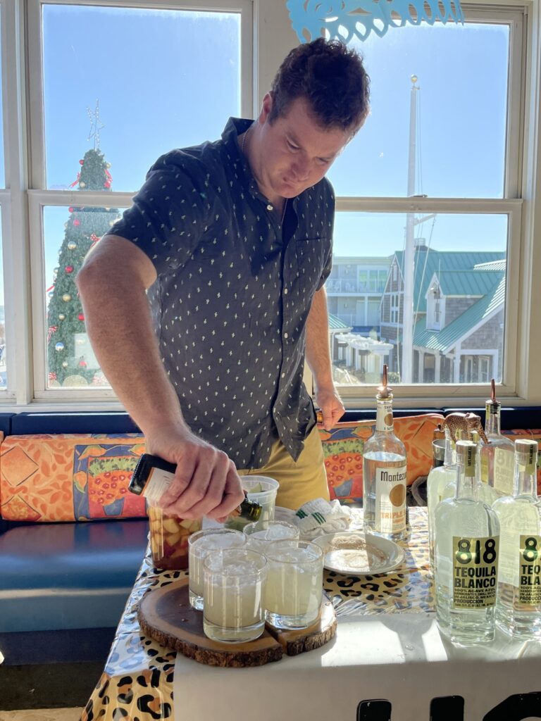 a man standing at a table with bottles of alcohol