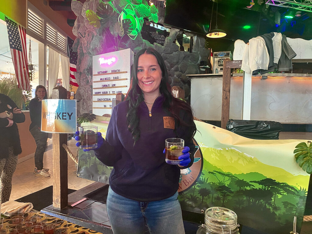 a woman holding a glass of beer in front of a painting