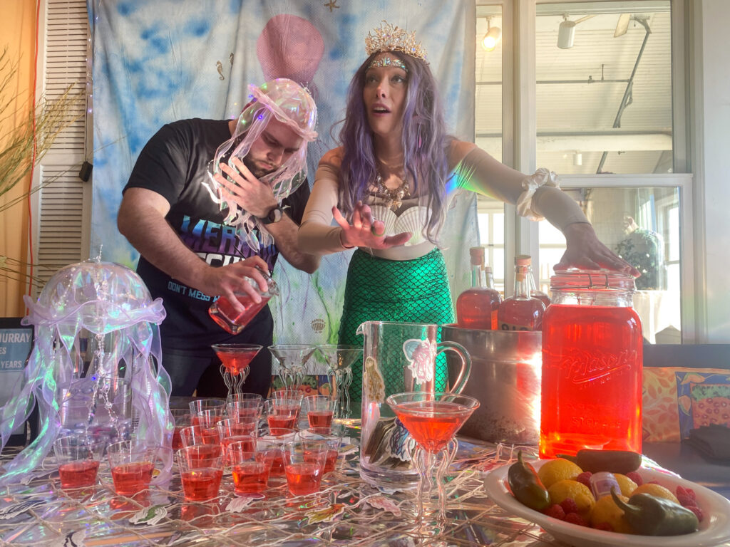 a man and a woman standing in front of a table filled with drinks