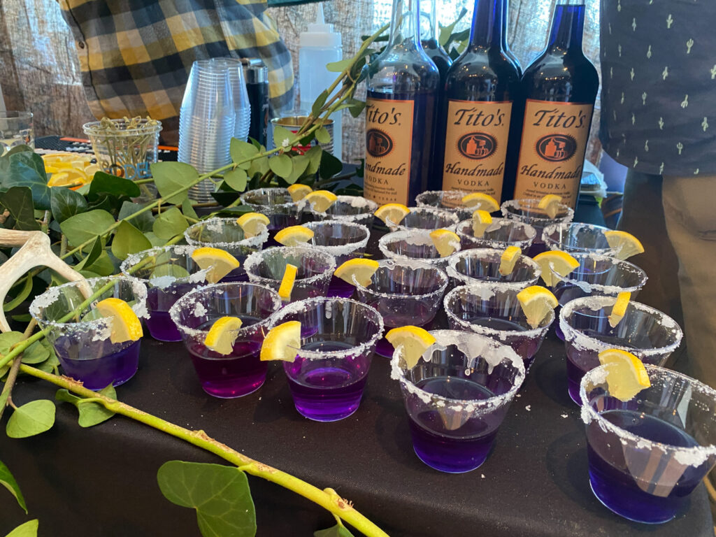 a table topped with lots of glasses filled with purple liquid