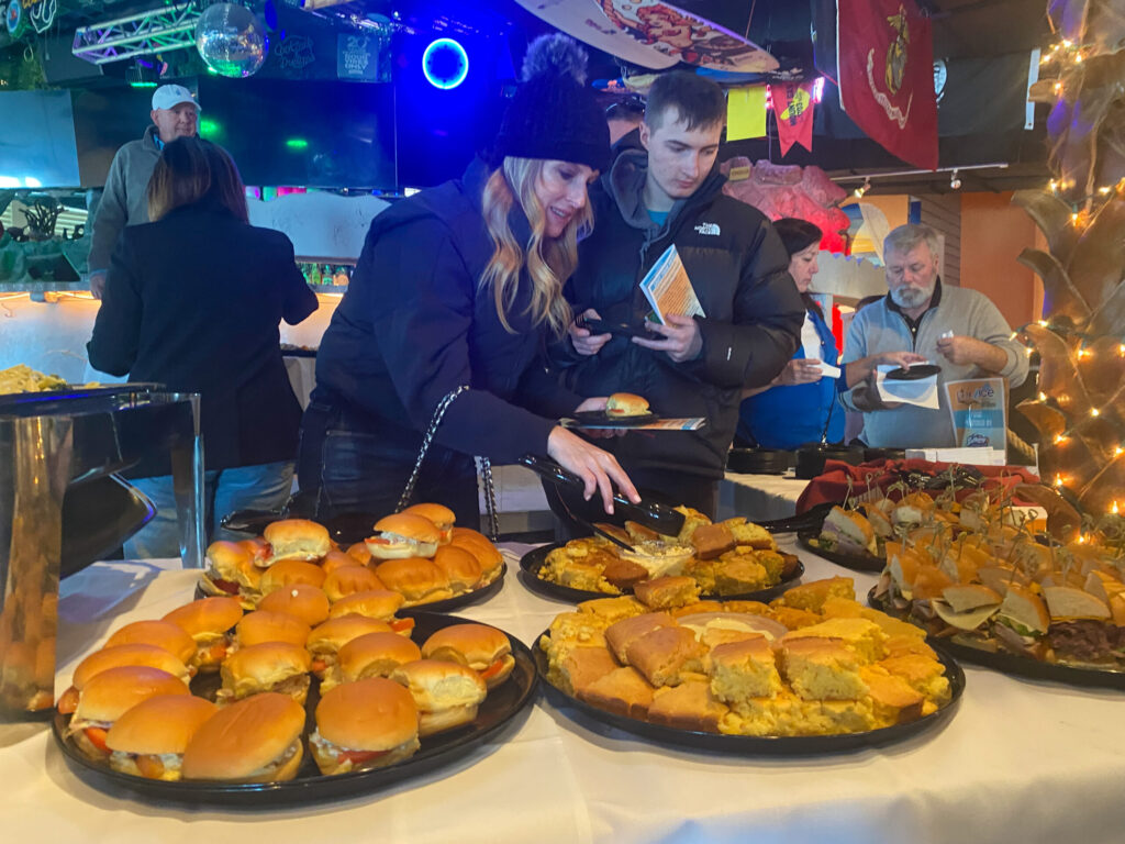 a group of people standing around a table filled with food