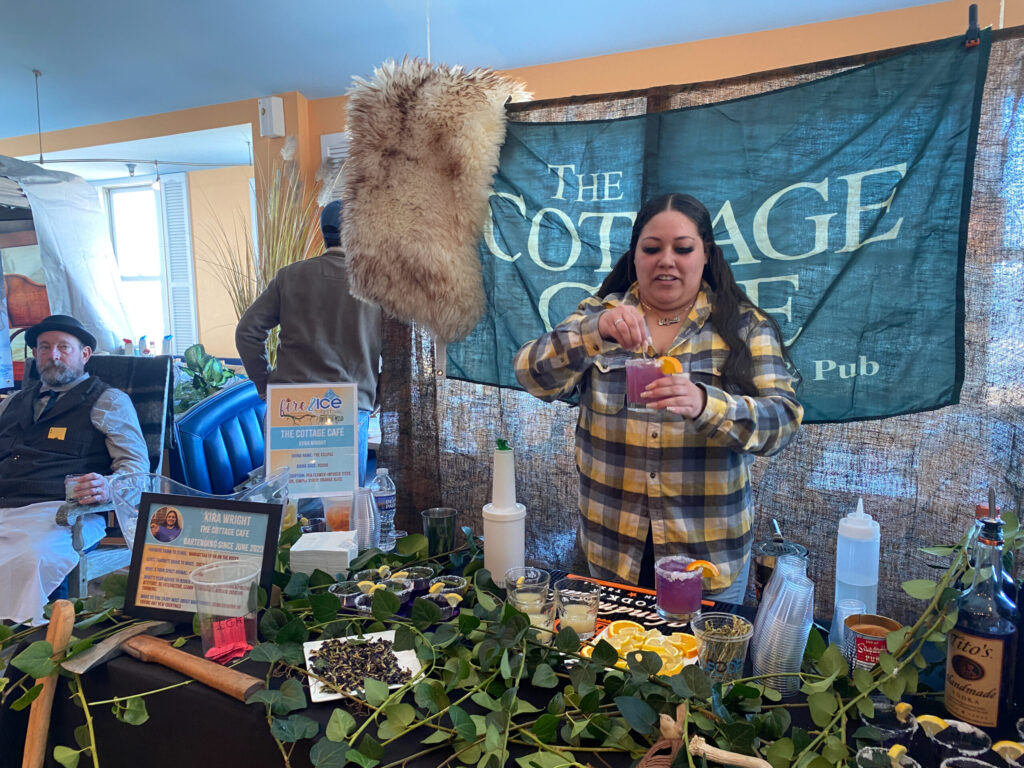 a woman standing in front of a table filled with plants