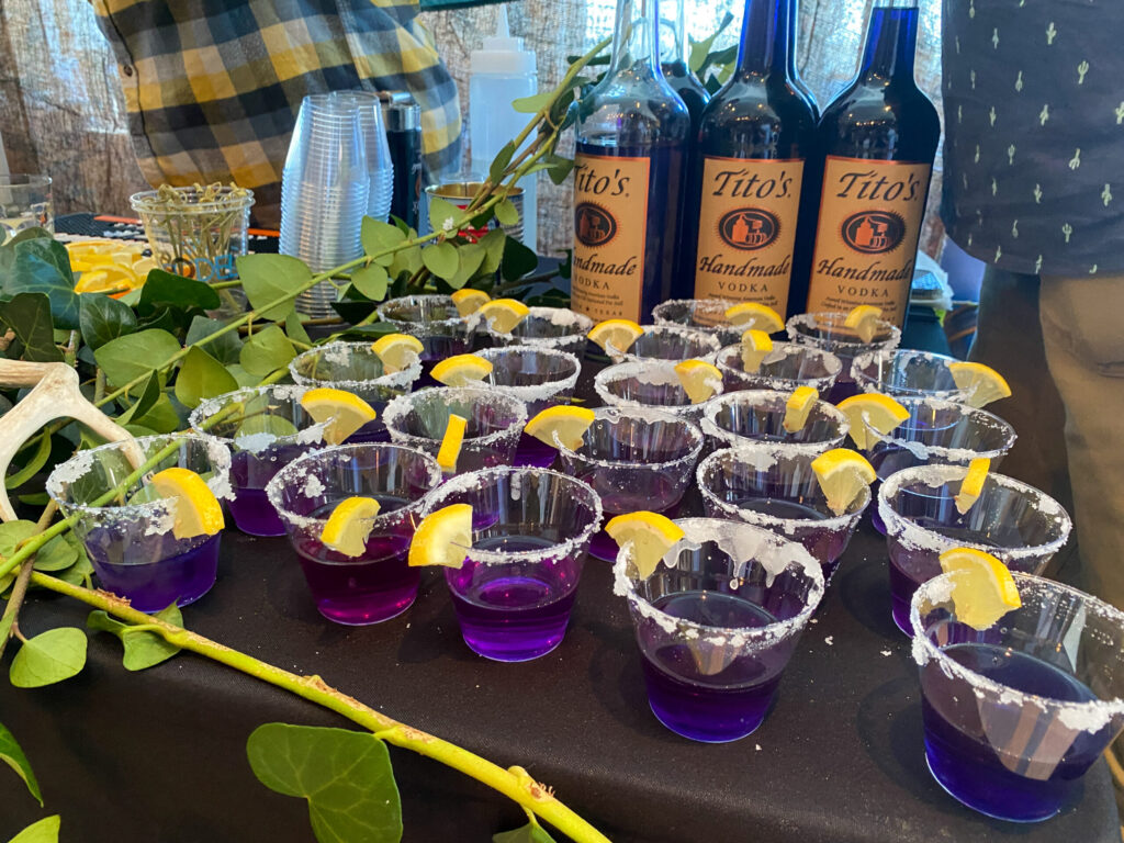 a table topped with lots of glasses filled with purple liquid