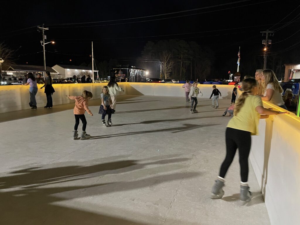 a group of people skating on an ice rink at night