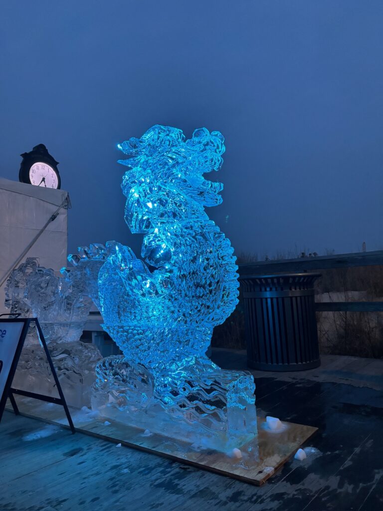 a sculpture of a dragon on a platform with a clock in the background