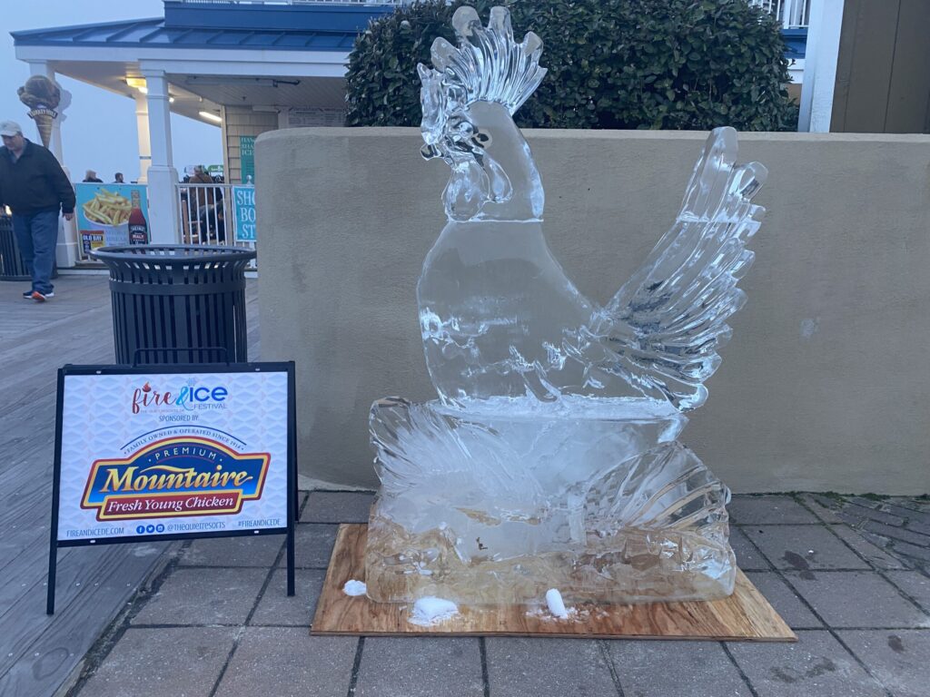 a statue of a chicken sitting on top of a wooden block