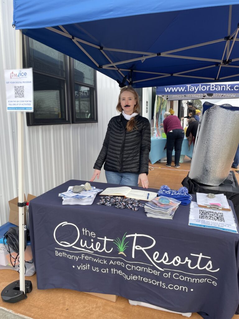 a woman standing next to a table under a blue tent