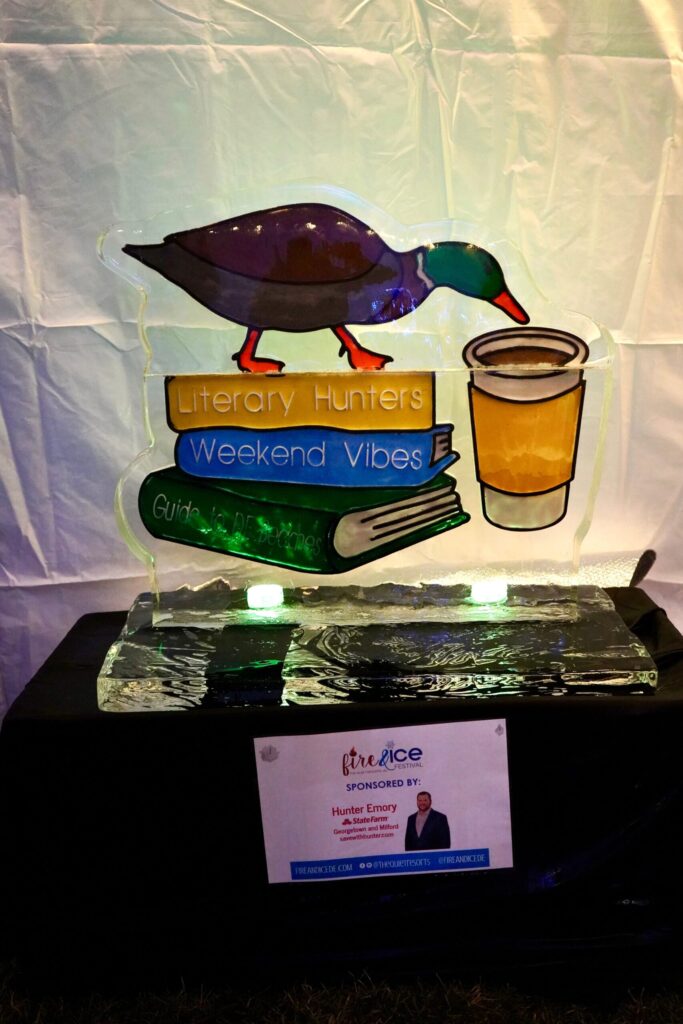 a glass sculpture of a duck with a book and a cup of tea