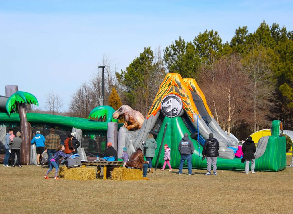 a group of people standing around a large inflatable slide