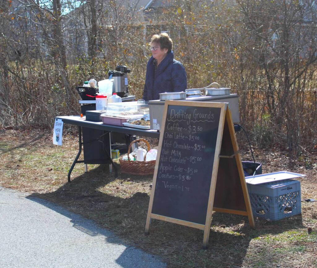 a woman standing behind a table with a sign on it