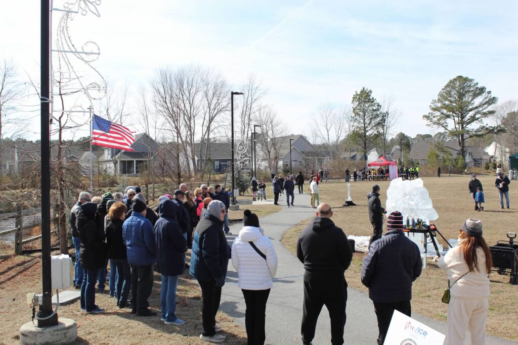 a group of people standing on a road next to a flag pole