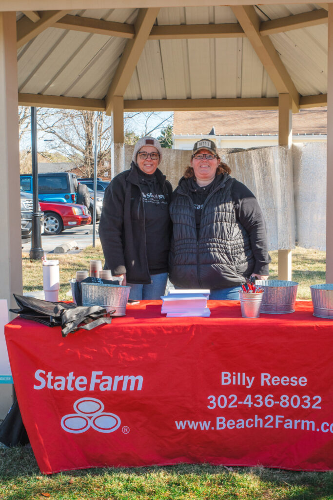 two people standing behind a red table with a sign that says state farm