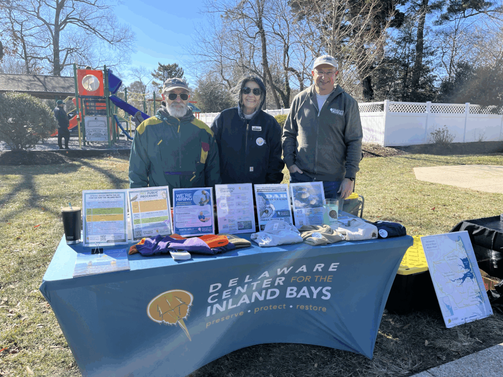 three people standing next to a table with information on it