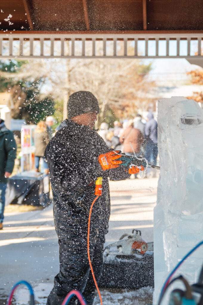 a man in a black jacket is using a snow blower