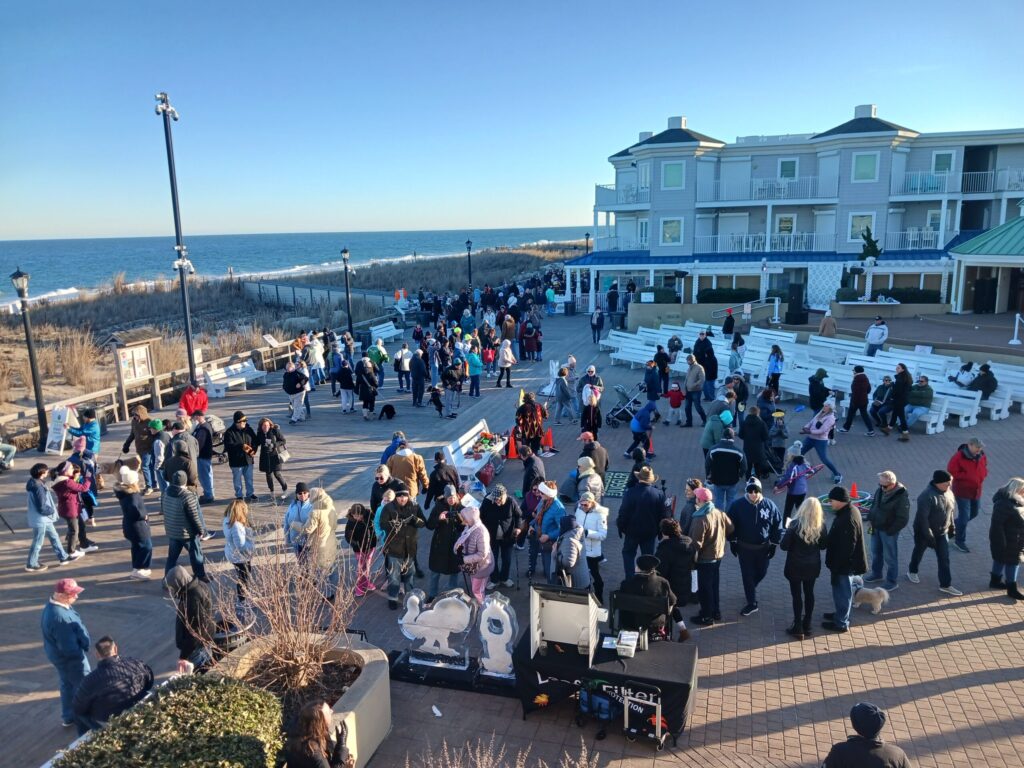 a crowd of people standing around a parking lot next to the ocean