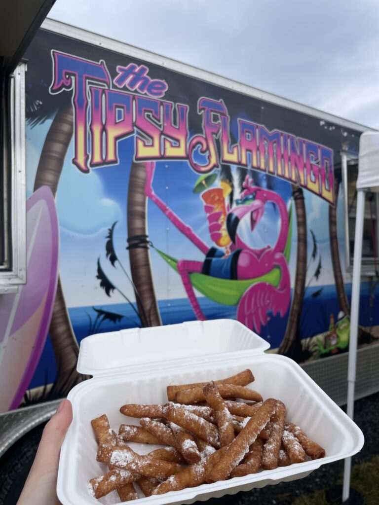a person holding a container of food in front of a food truck