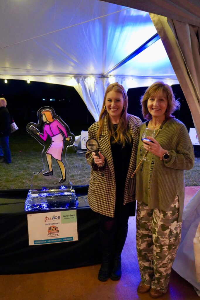 two women standing next to each other in front of a tent