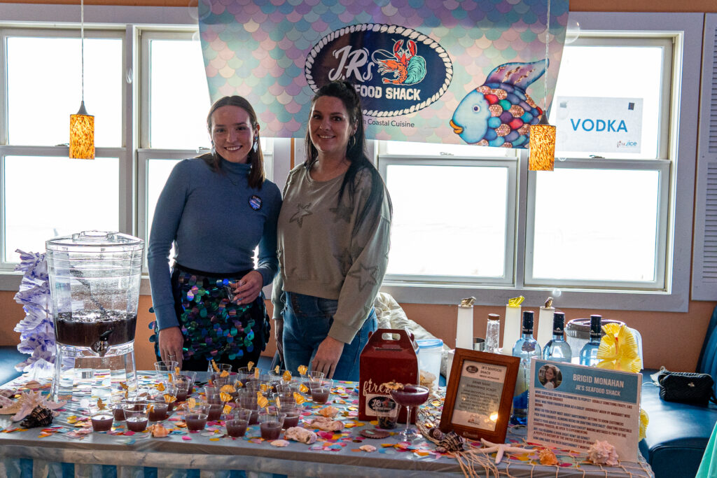 two women standing in front of a table covered in cupcakes