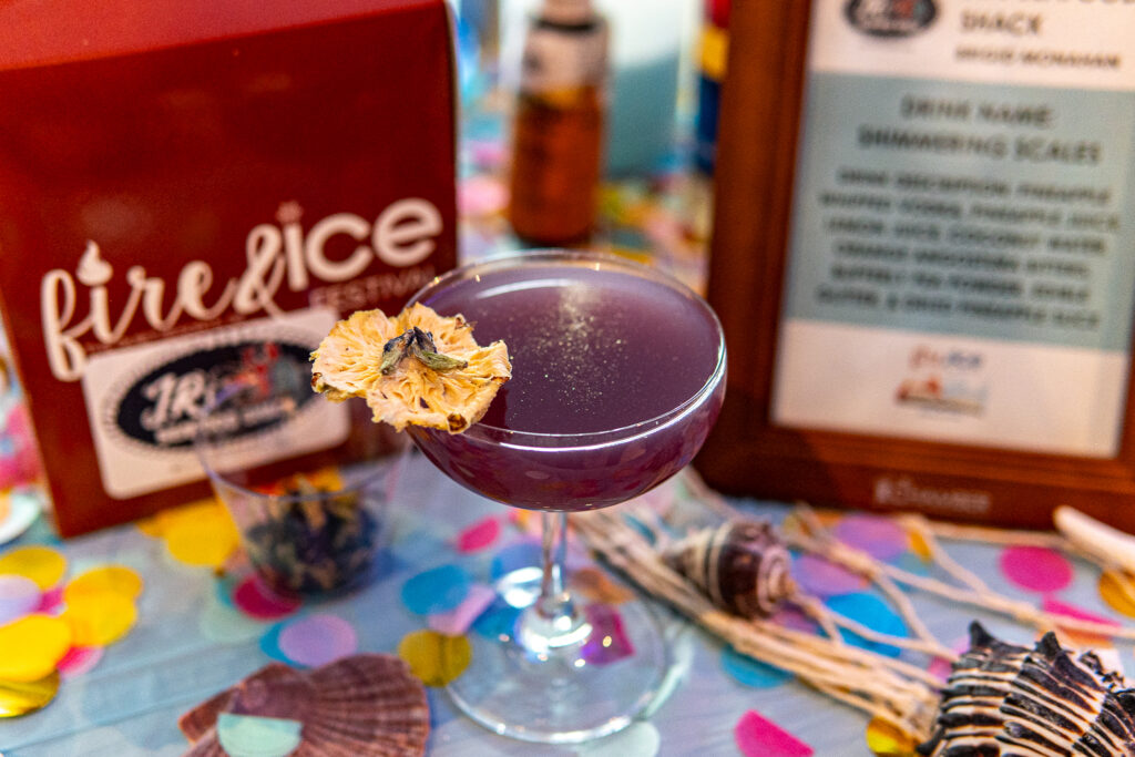 a purple cocktail with a flower garnish on the rim
