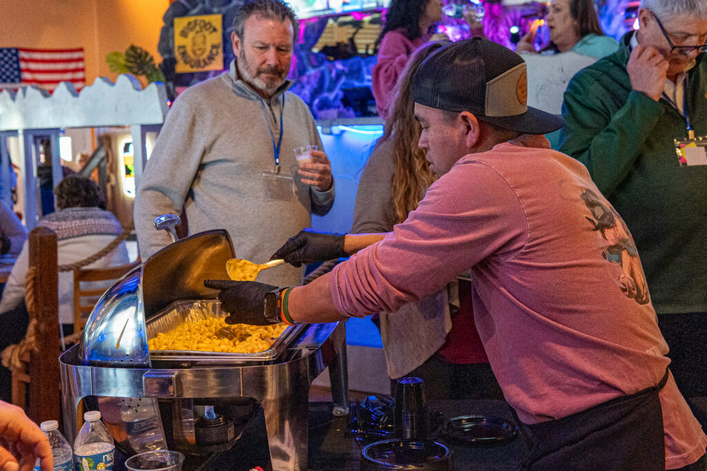 a group of people standing around a table filled with food