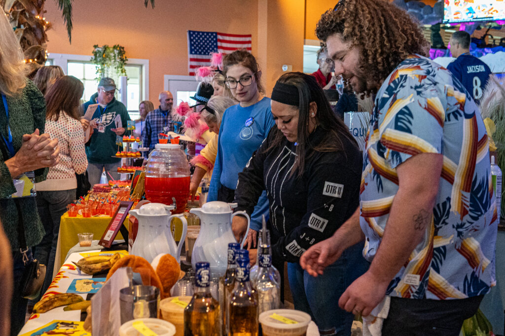 a group of people standing around a table filled with food