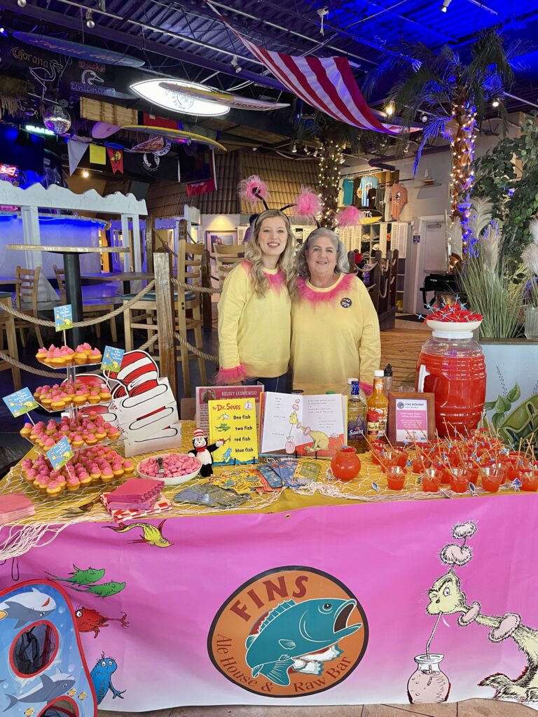 two women standing in front of a table full of food