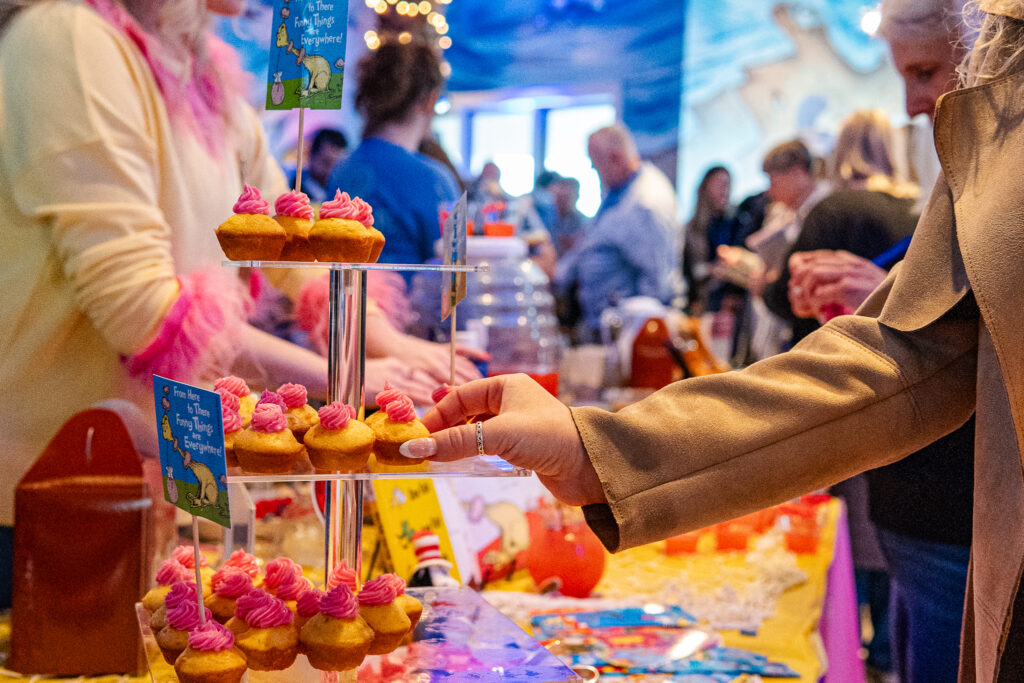 a woman reaching for a cupcake on a table