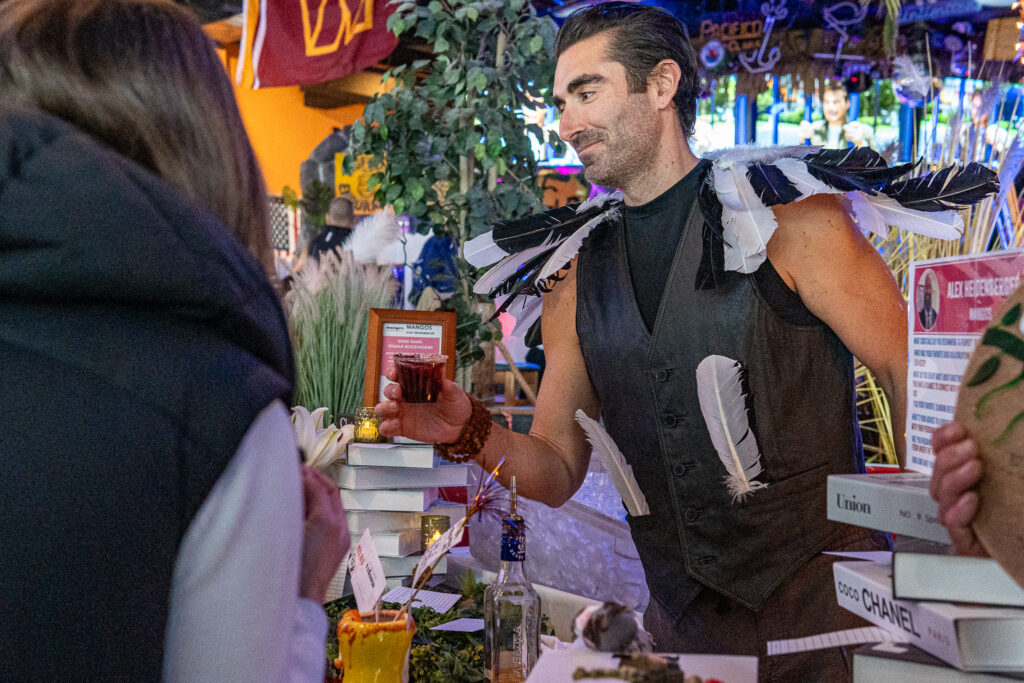 a man standing in front of a bar with a drink in his hand