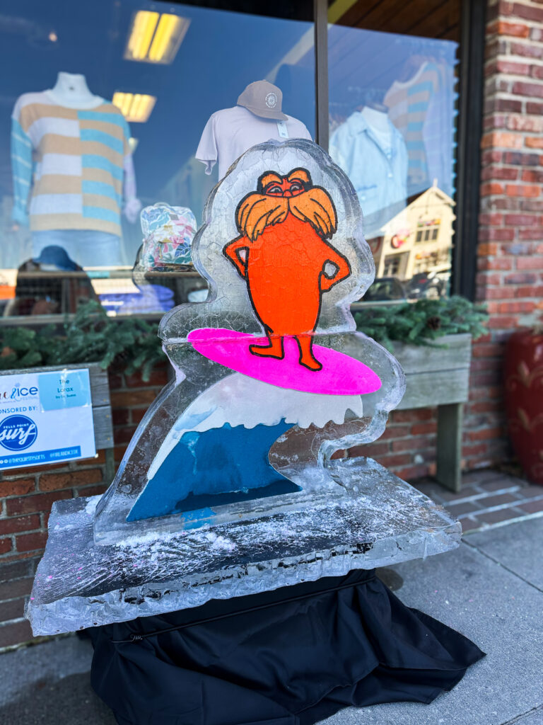 a glass sculpture of a woman holding a surfboard in front of a store