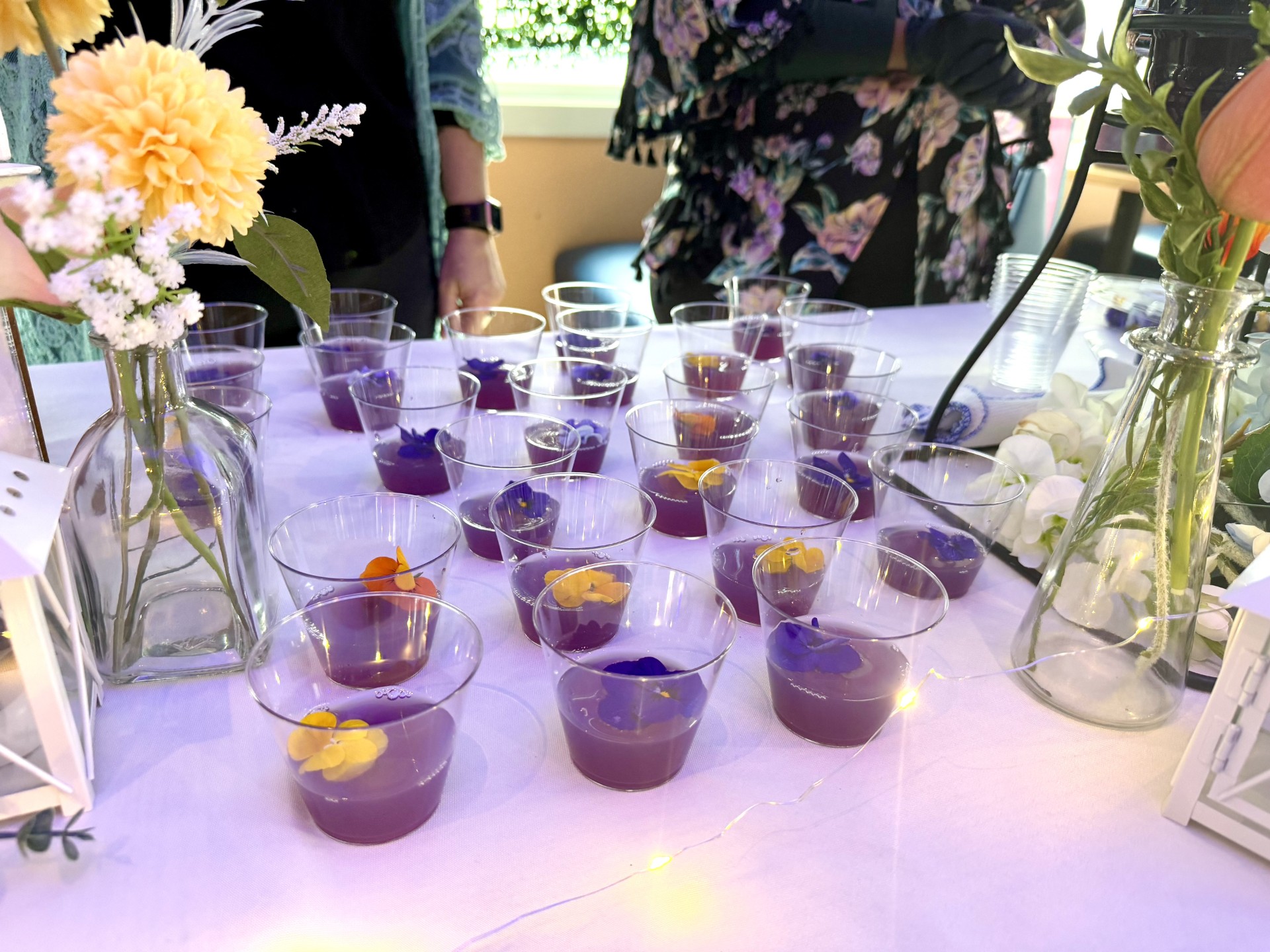 a table topped with lots of glasses filled with purple liquid