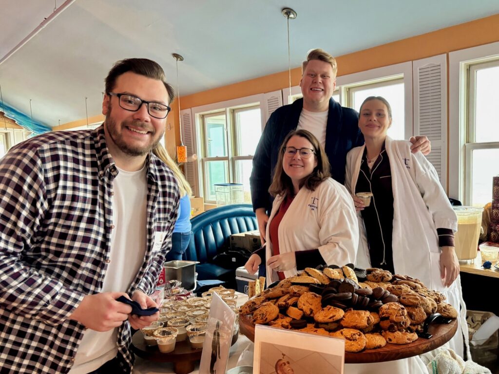 a group of people standing around a table filled with food